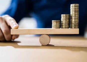 Vemos una imagen de la inlación mundial 2022 con una persona sosteniendo un balancín con monedas del otro lado