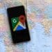 Vemos por qué no aparece mi negocio en google maps con una imagen de un celular con la app google maps sobre un mapa mundial de papel.