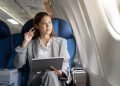 Vemos una imagen de una mujer sentada con una computadora en un avión, referido a negocios para ser millonario