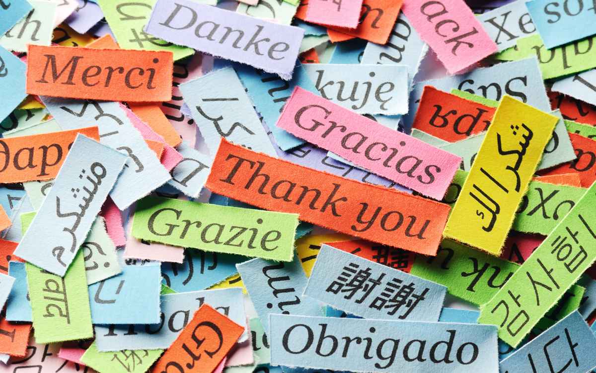 Vemos una imagen de muchos papeles con la frase gracias en diferentes idiomas, en referencia al uso de frases cortas de agradecimiento para clientes por su preferencia.