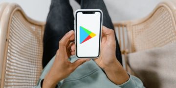 Persona sosteniendo celular con ícono de Play Store