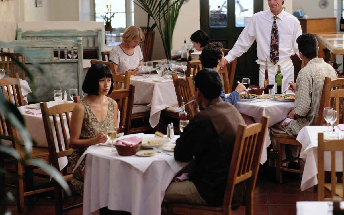 Vemos una imagen de un restaurante con personas y meseros, en referencia a la elaboración de un estudio de mercado de un restaurante.