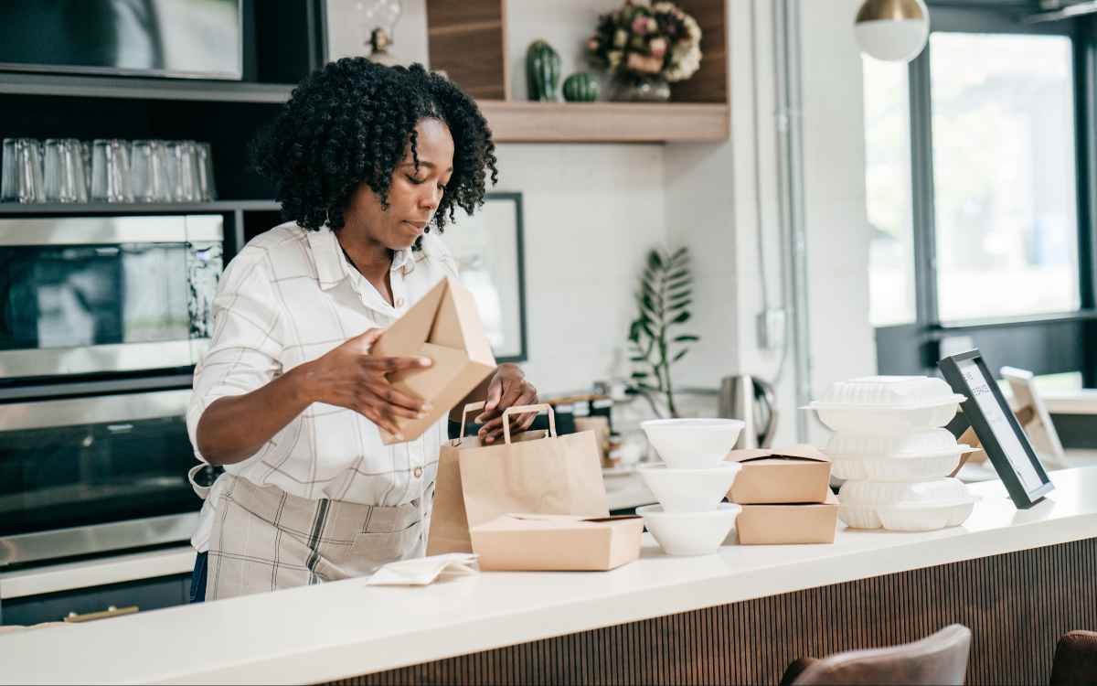 Vemos una imagen de una mujer preparando pedidos de un delivery, en referencia a los datos sobre consumo en la encuesta de estudio de mercado de un restaurante.