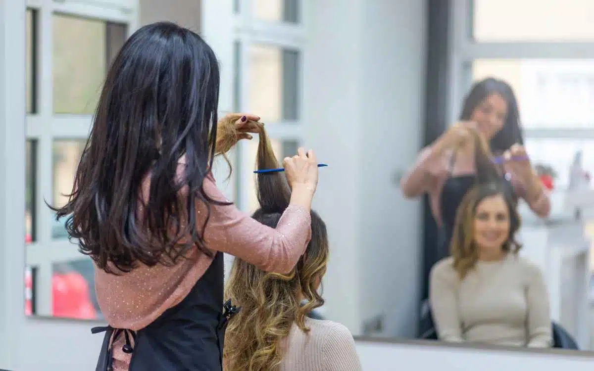 Vemos una imagen de una peluquera trabajando el cabello de una clienta, en referencia al proceso de buscar nombres para salones de belleza.