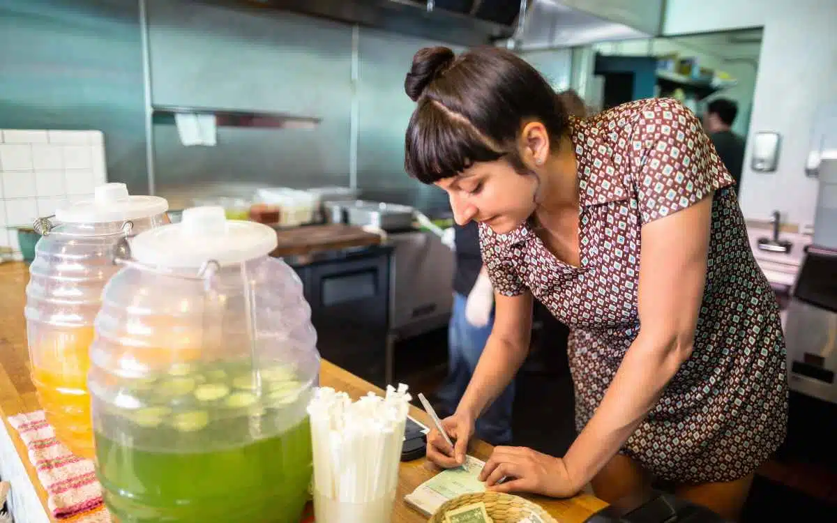 Vemos una imagen de una mujer tomando pedidos en un restaurante de tacos, en relación con la búsqueda de nombres para taquerías.