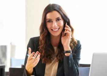 Vemos una imagen de una mujer con un teléfono brindando asesoría, en relación con buscar ideas de nombres para empresas de consultorías.