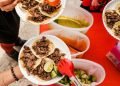 Vemos una imagen de personas consumiendo tacos en un pequeño negocio, en relación con ideas de nombres para taquerías.