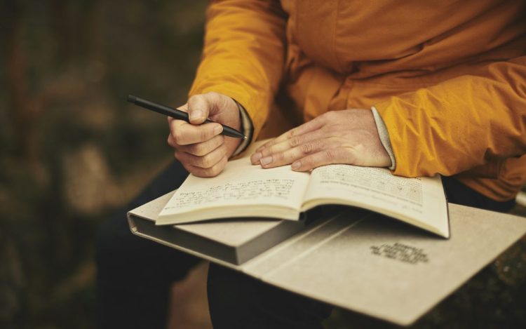 una mujer escribe en un cuaderno haciendo la práctica del journaling