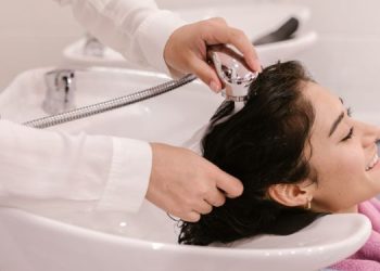 Vemos una imagen de una mujer lavando el cabello de otra persona, en referencia a la búsqueda de nombres para salón de belleza.