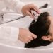 Vemos una imagen de una mujer lavando el cabello de otra persona, en referencia a la búsqueda de nombres para salón de belleza.