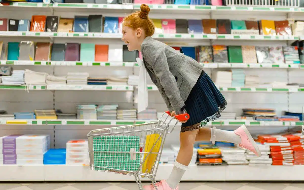 Vemos una imagen de una niña jugando con un carro de compras en una tienda de variedades.