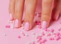 Vemos una imagen de unas uñas pintadas en un fondo rosa combinado, en relación con la creación de logos para negocio de uñas.