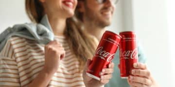 Vemos una imagen de una pareja sosteniendo unas latas de Coca Cola, en relación con la historia de la publicidad de Coca Cola.