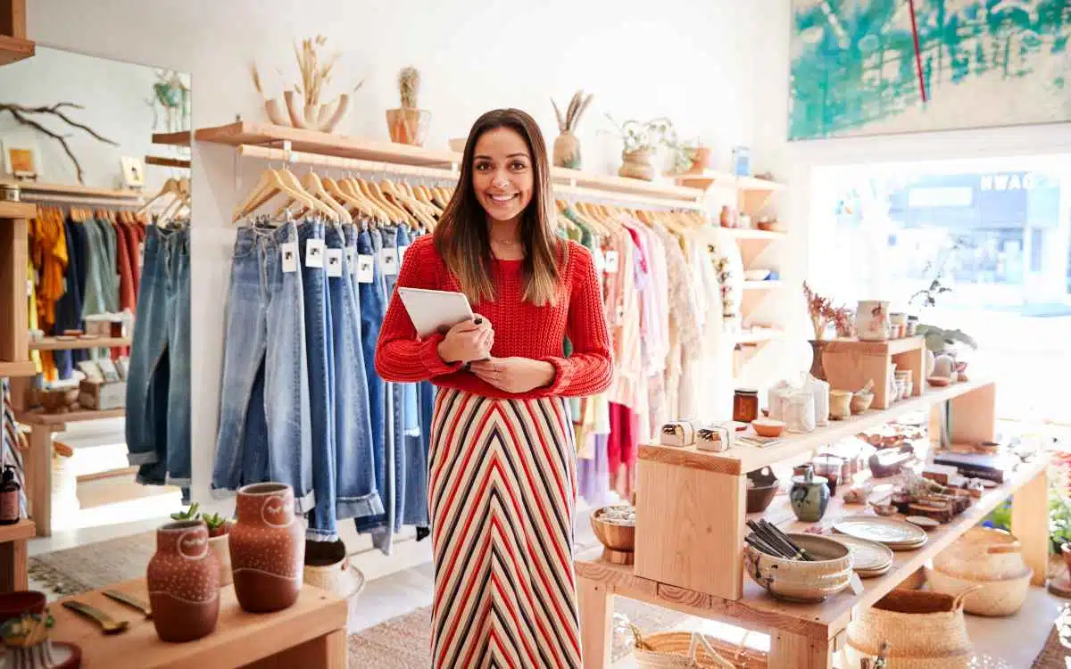 Vemos una imagen de una emprendedora en su negocio, en referencia a cómo emprender un negocio de ropa.
