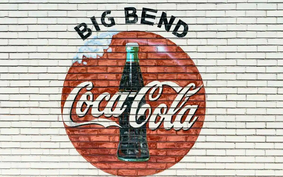 Vemos una imagen de una publicidad pintada en una pared de Coca Cola, en referencia al modelo de negocio de Coca Cola. 