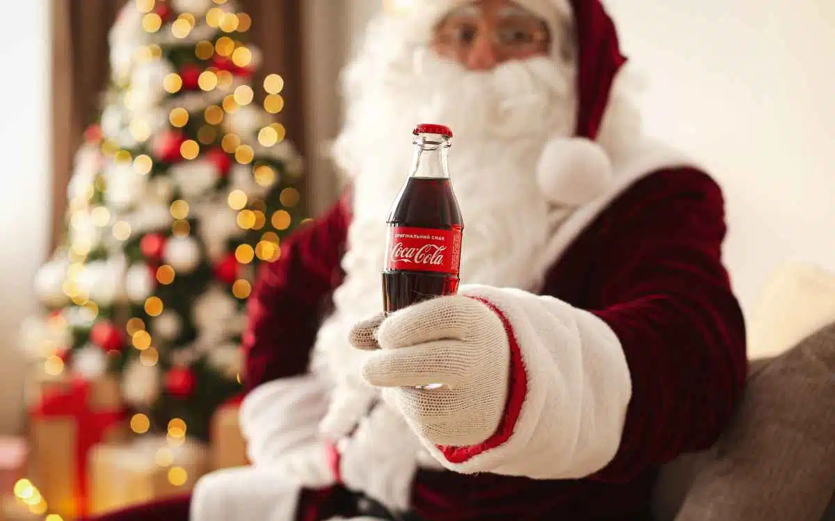 Vemos una imagen de un Papa Noel sosteniendo una Coca Cola, en relación con los valores de la misión y visión de Coca Cola.
