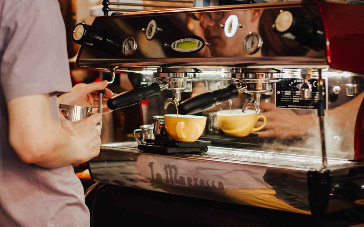 Vemos una imagen de una persona trabajando con una máquina de café, en referencia a las franquicias de café.