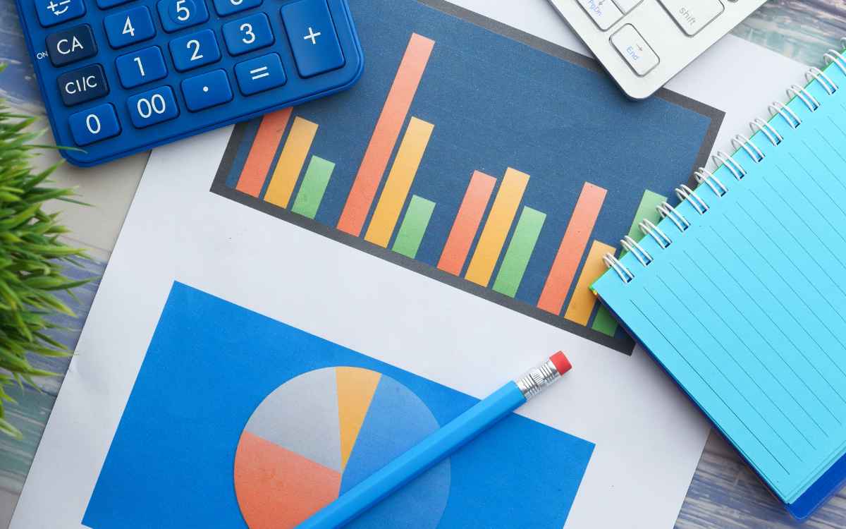 Imagen de una hoja de métricas de marketing, con otros objetos como calculadora y cuadernos, en referencia a la importancia de la mercadotecnia y sus beneficios.