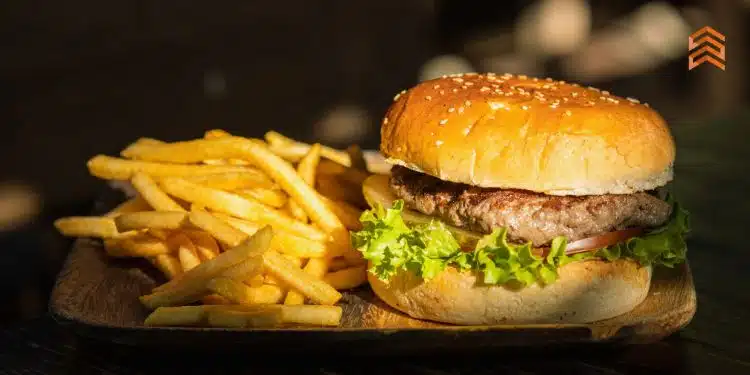 Vemos una imagen de una hamburguesa con papas en un plato, en referencia a nombres para negocios de hamburguesas.