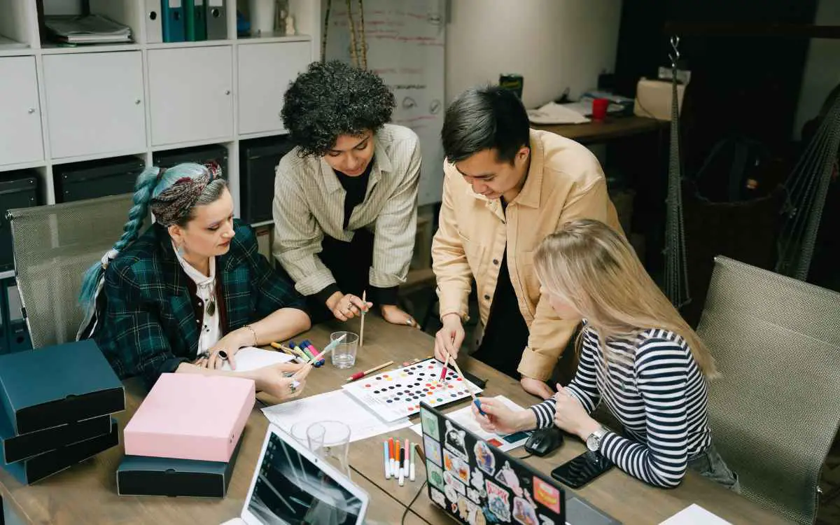 Imagen de cuatro personas trabajando en un departamento de marketing, en referencia a la importancia de la mercadotecnia y su organización departamental.