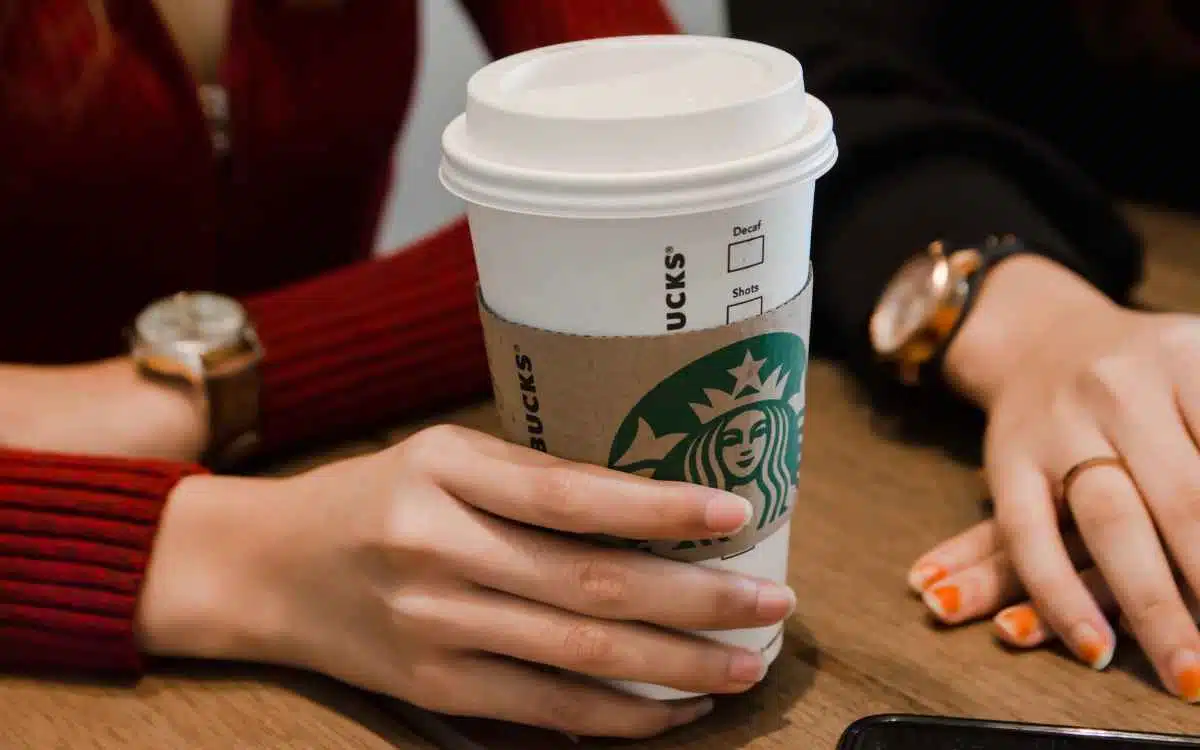 Vemos una persona sosteniendo un vaso de Starbucks, en referencia a la misión y visión de Starbucks.
