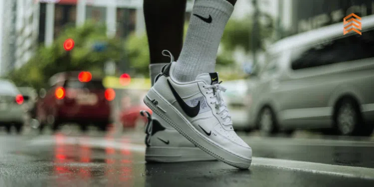 Vemos una imagen de una persona mostrando sus zapatillas Nike en un paisaje urbano, en relación con la misión y visión de Nike.