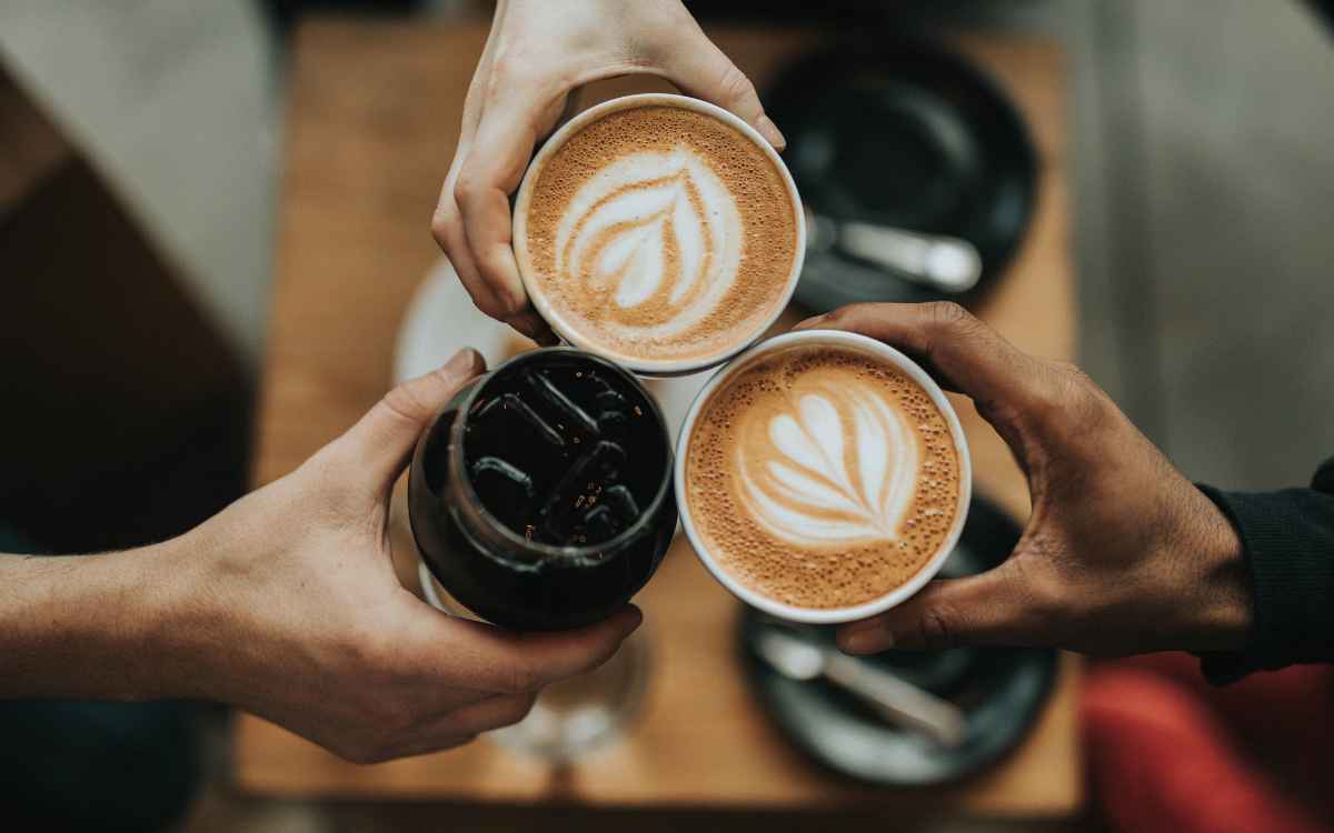Vemos tres personas mostrando diferentes variedades de café, en referencia a la búsqueda de nombres para cafeterías.