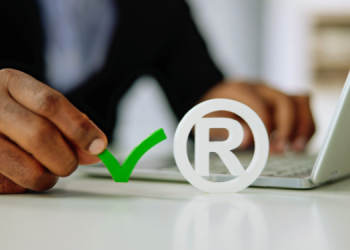 Vemos una imagen de una persona usando la computadora con el símbolo R, en referencia a cómo registrar una marca.