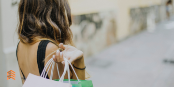 Vemos una imagen de una mujer con bolsas de shopping, en relación con los motivos de compra de los consumidores.