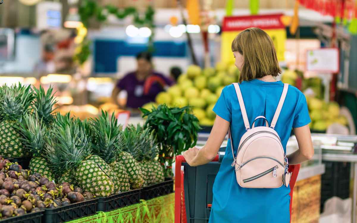 Vemos una mujer en un supermercado observando productos comestibles, en relación con los motivos de compra.