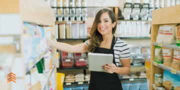 Vemos a una empleada de una empresa naturista acomodando precios y revisando productos.