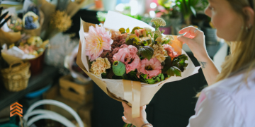 Vemos una persona creando un arreglo de flores, en relación con la búsqueda de nombres para florería.