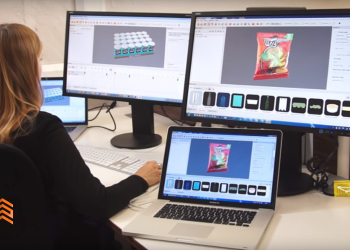 En la imagen se ve una chica de espalda trabajando con 3 computadoras.