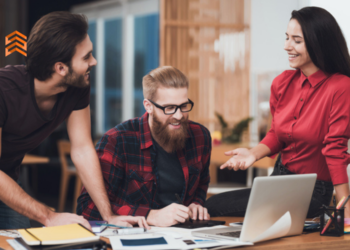 En la imagen se ve a 3 personas trabajando con una computadora. (Nombres para empresas de marketing)