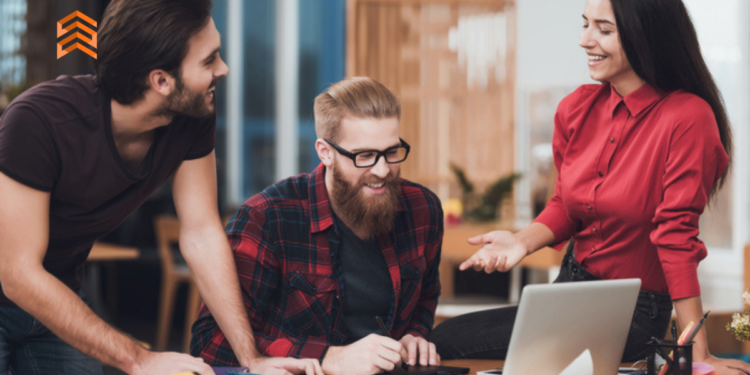 En la imagen se ve a 3 personas trabajando con una computadora. (Nombres para empresas de marketing)