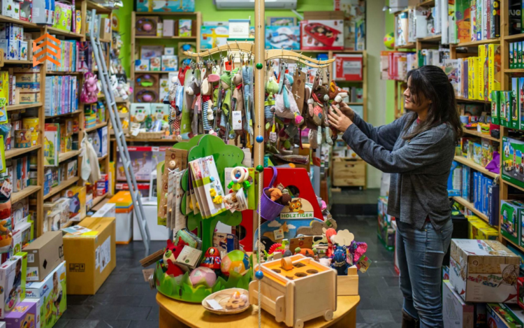 En la imagen se ve a una mujer en una tienda eligiendo regalos