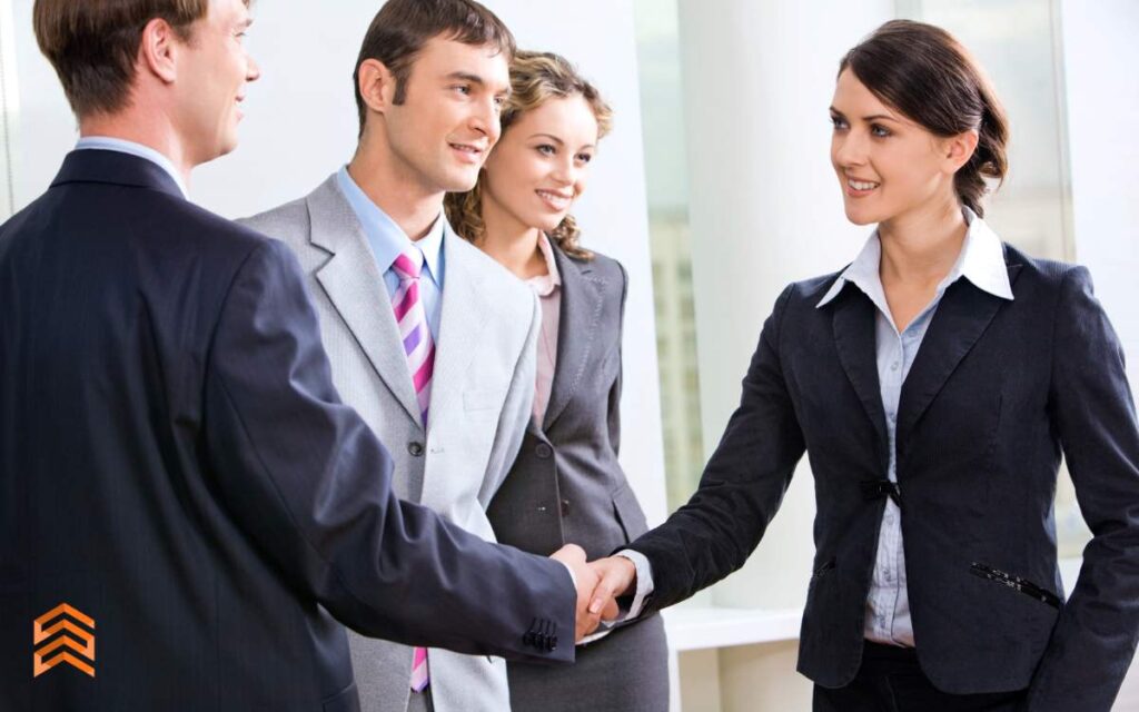 Un grupo de personas en trajes de negocios dándose la mano, representando la fase de 'Acción' del método AIDA.