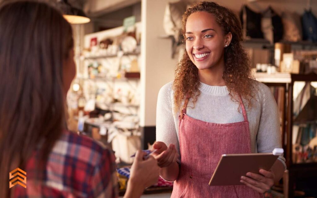 Una vendedora sonriente atendiendo a una clienta en una tienda, ilustrando la fase de 'Atención' del método AIDA.