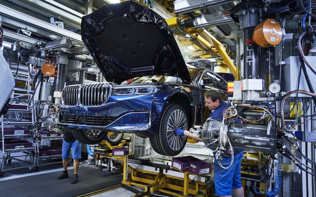 En la imagen se ve un auto BMW en la fábrica mientras dos personas lo revisan- (organigrama de BMW)